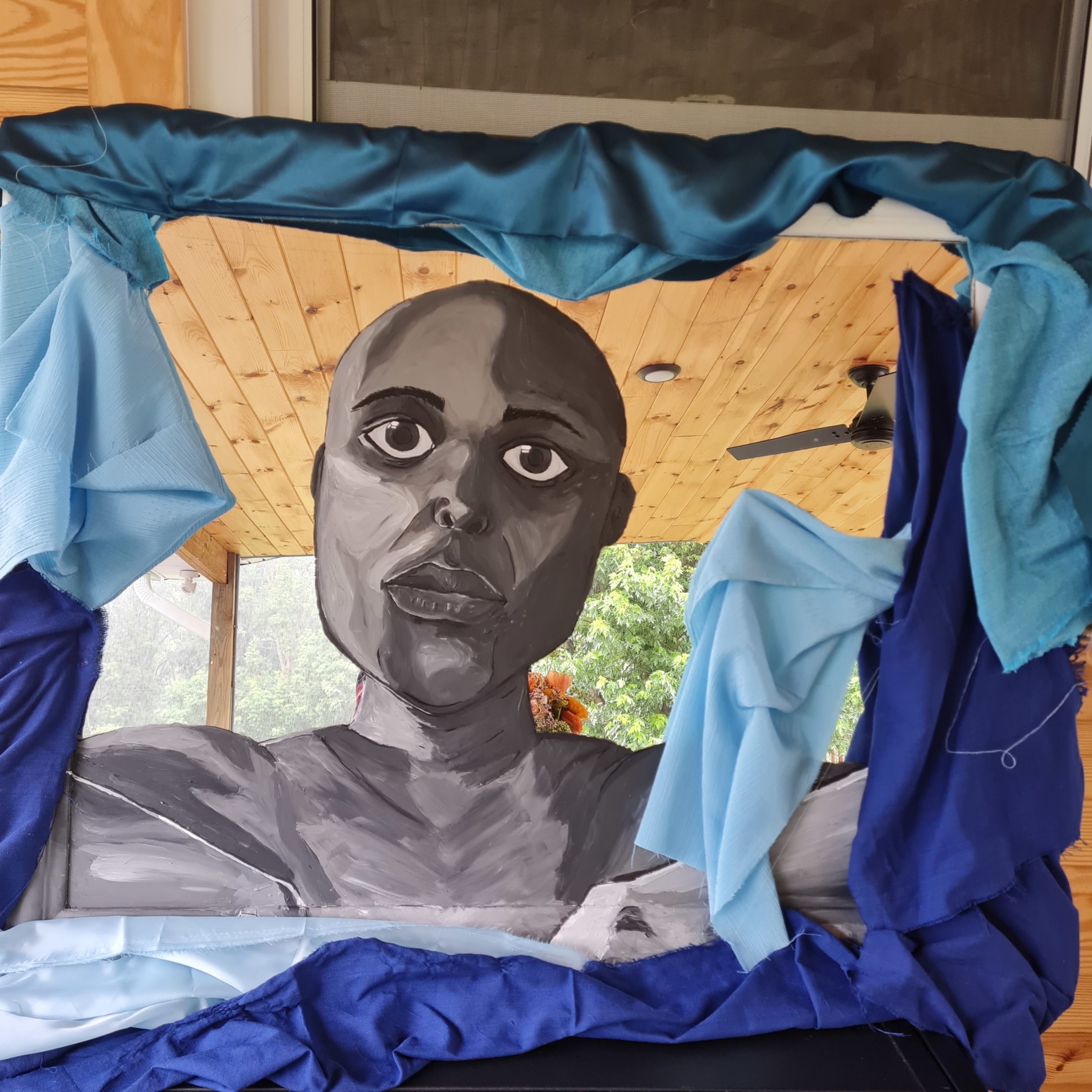 Mixed media painted self portrait of artist Karen Wangare Leonard. Painted on a mirror with fabric draped around the edges.