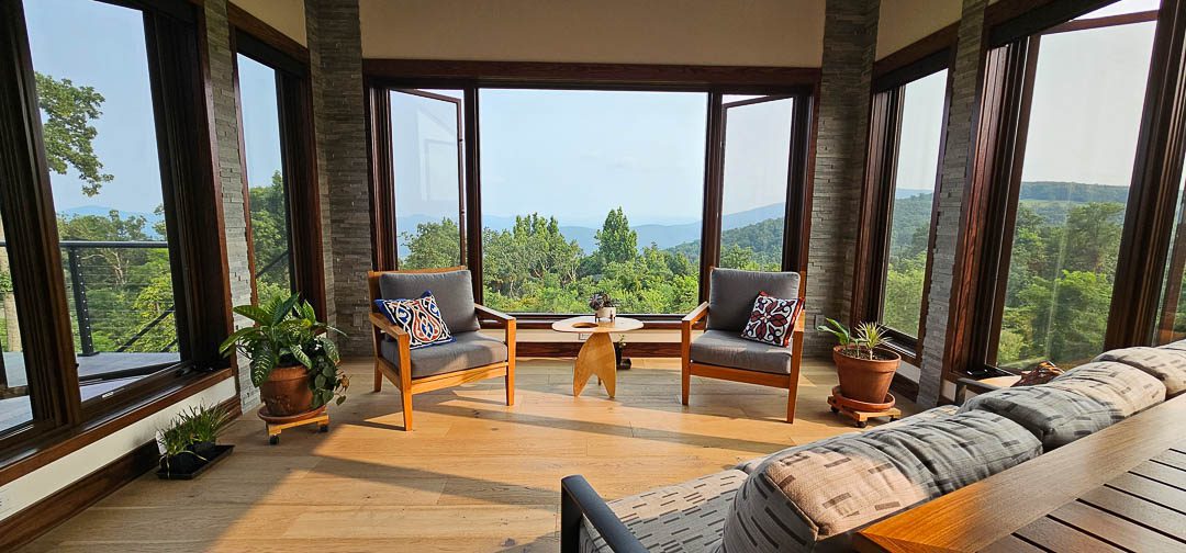 living room with two chairs and a sofa looking out to the views through large windows on three sides.