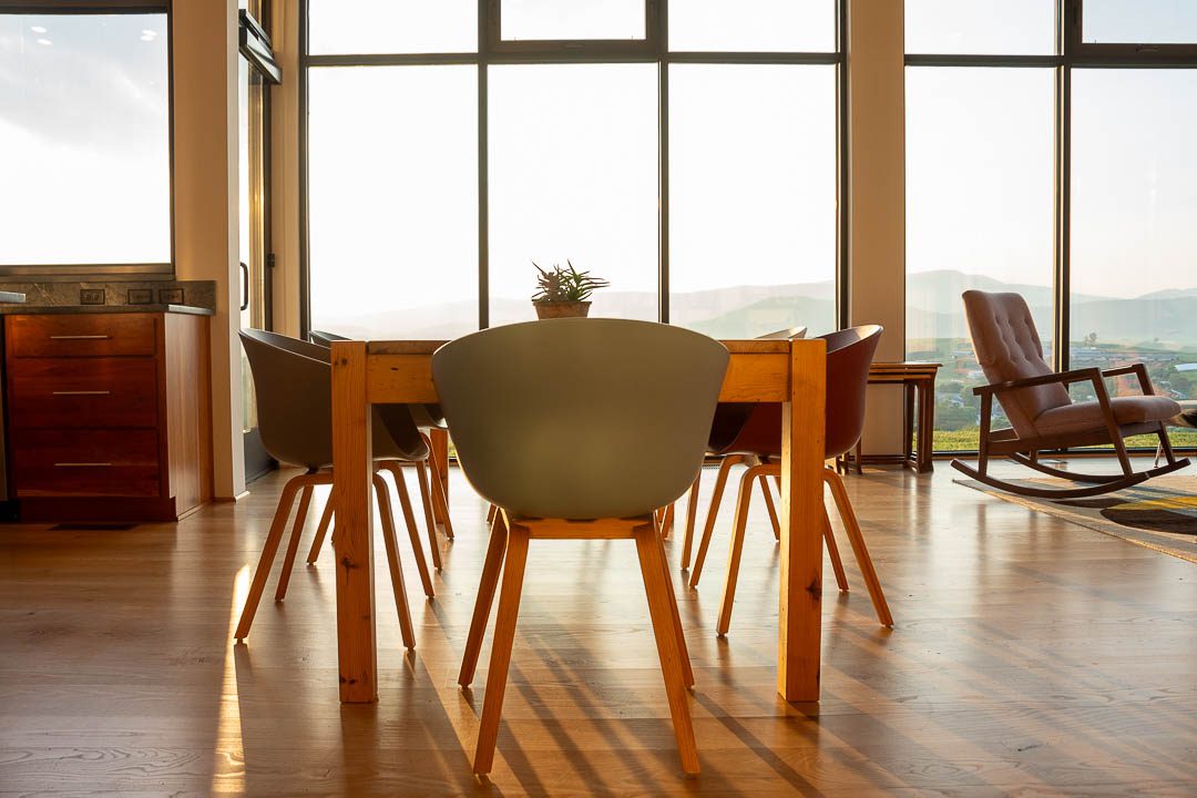 dining table with sun streaming through the window walls behind.
