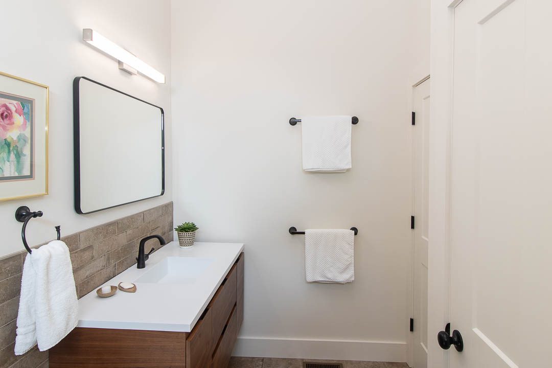 secondary bathroom. sink and mirror, towels hanging on wall.