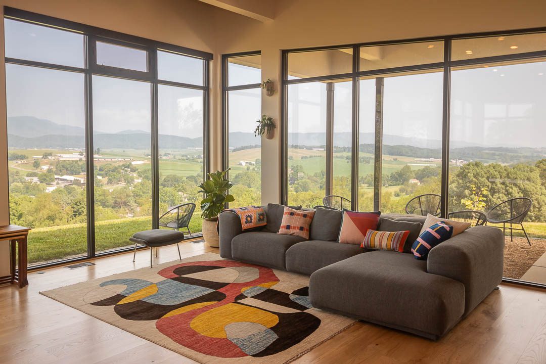 living room couch. a wall of windows behind overlooking the mountains.
