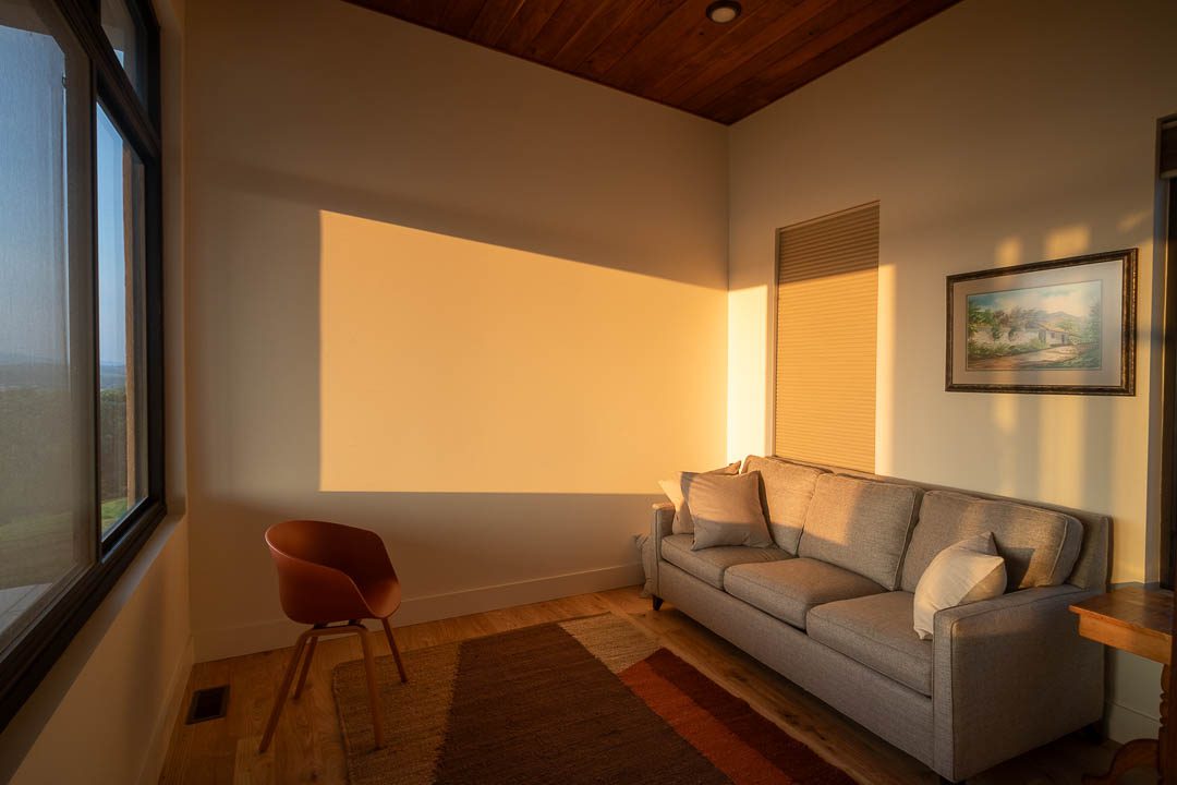 bonus room with couch and chair. Light during golden hour streams through the window.