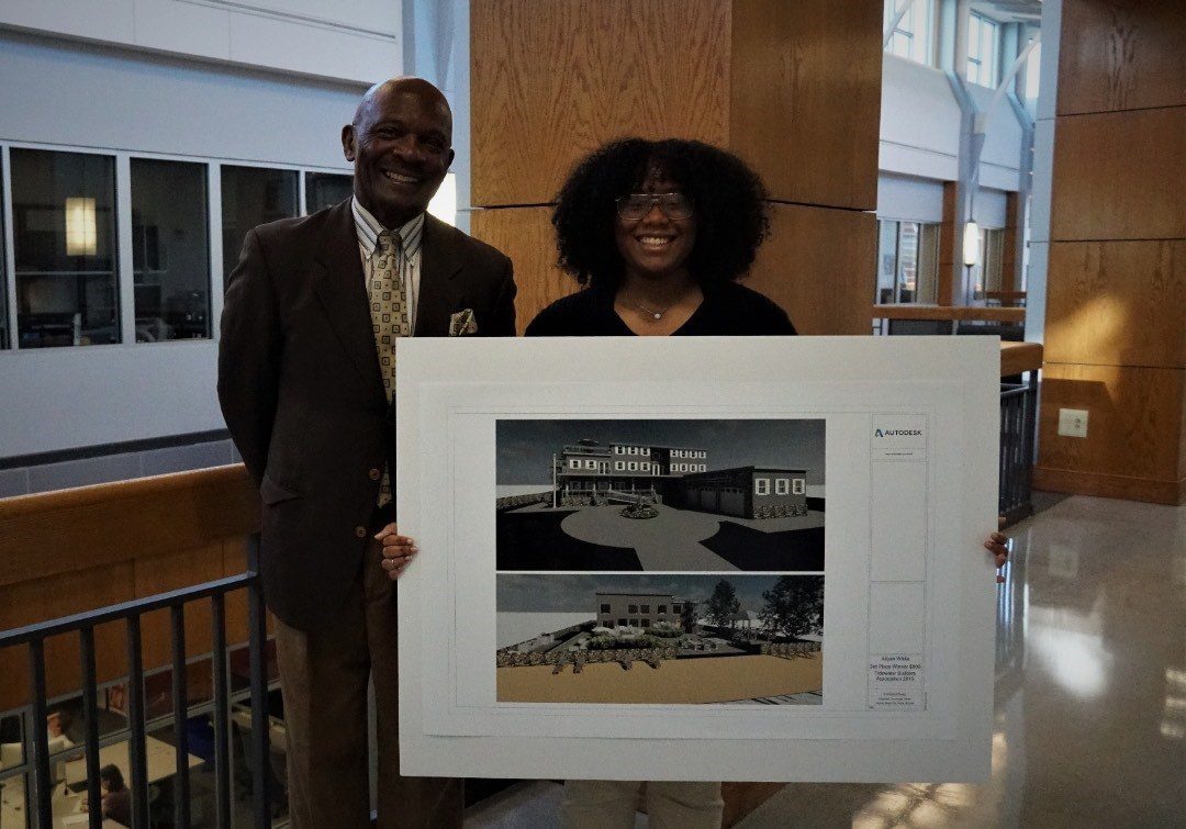 Aliyah with her teacher in highschool. She holds a poster while winning third in a high school design competition.