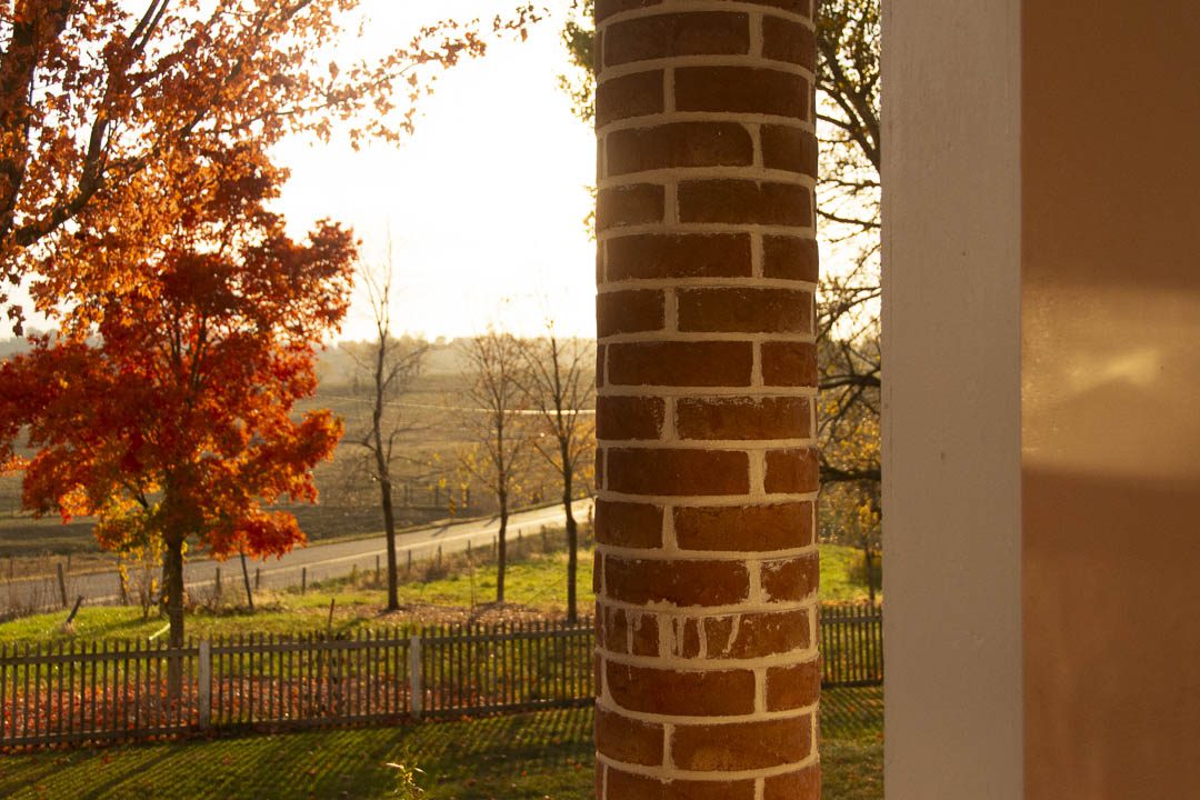 Round brick column on historic porch. View looking into the rising sun.